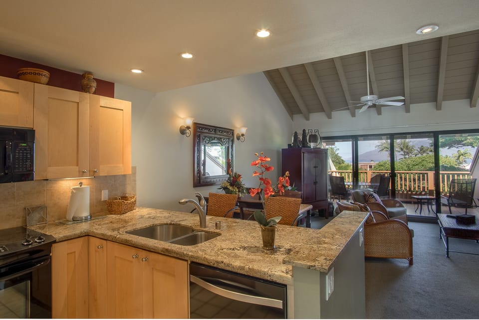 Step into your island retreat where the kitchen flows into a bright living space, framed by vaulted ceilings and mountain views through sliding glass doors leading to your private deck.