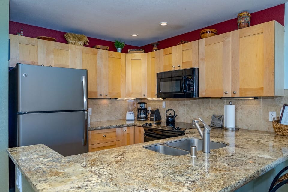 Your fully equipped kitchen invites you to prepare meals at your leisure, featuring granite countertops, modern appliances, and warm wood cabinetry for a home-away-from-home cooking experience.