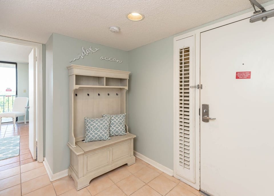 The entryway features a stylish bench with decorative pillows, perfect for storing beach gear and relaxing