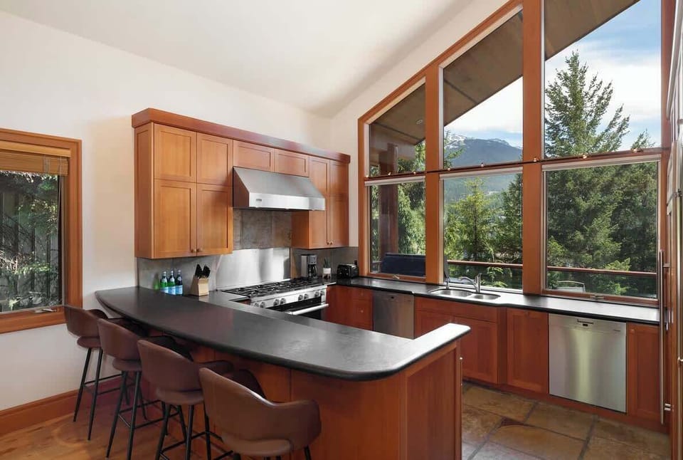 - Spacious kitchen with bar seating and panoramic forest and slope views  
- Modern appliances and wooden finishes offer both style and function  
- Perfect spot for morning coffee or après-ski gatherings with friends  
