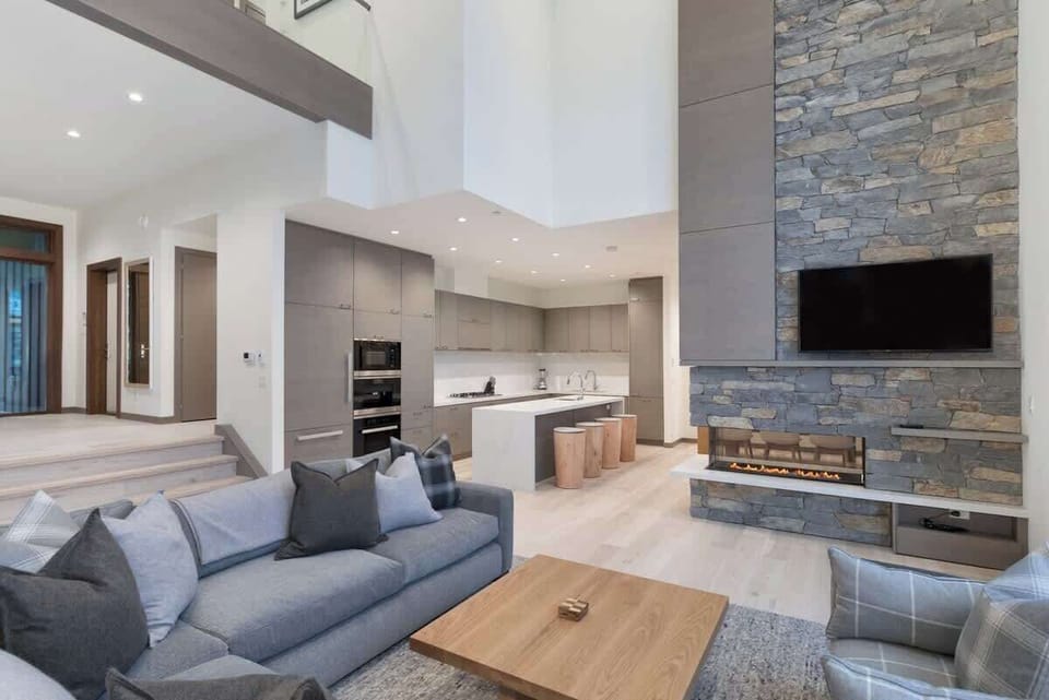 - Inviting living room with stone fireplace and mountain views  
- Comfortable seating area beside open-concept kitchen  
- Great space to unwind after outdoor adventures or ski days  
