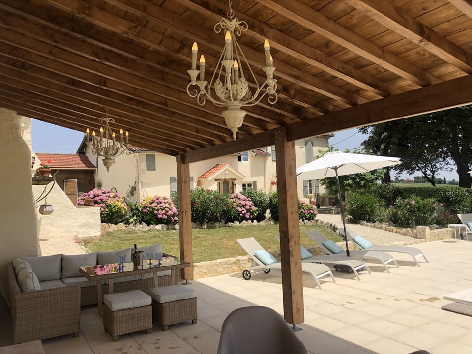Shady abri by the pool , with table and comfortable seating .