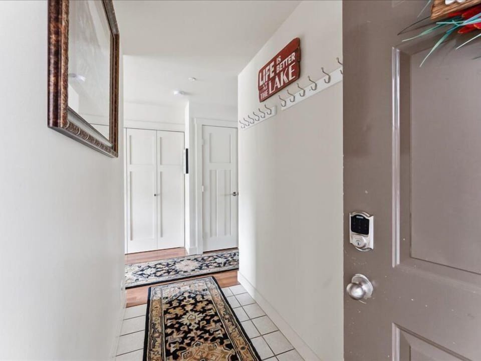 Arrive to a welcoming entryway with tile floors, decorative rugs, and clever coat hooks—'Life is Better at the Lake' sets the tone for your lakeside escape.