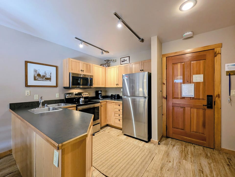 Your fully equipped kitchen features warm wood cabinetry, sleek stainless appliances, and granite countertops—perfect for preparing meals during your mountain getaway.