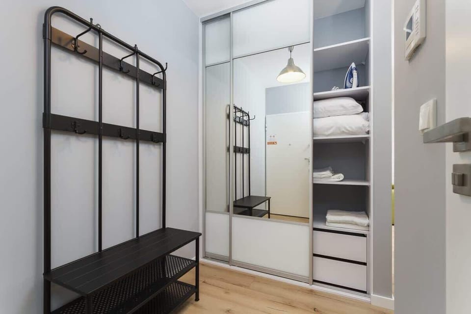Hallway with black coat rack and shoe shelf and large wardrobe with mirrored doors. 