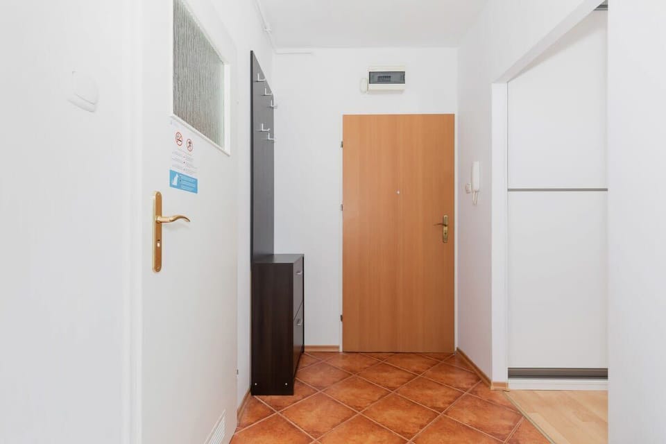 An entryway with a wooden door and intercom, giving a clean and functional look as part of the apartment's entrance area.