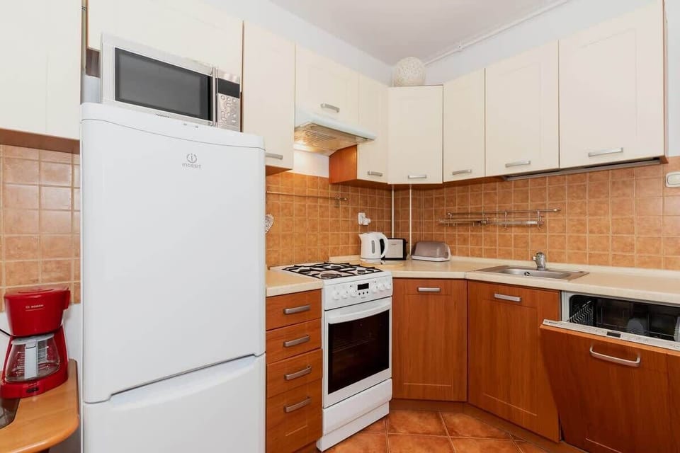  A view of a kitchen with wooden cabinetry and white appliances, including a refrigerator and oven. The countertops are clean, and the kitchen has a practical, functional design.