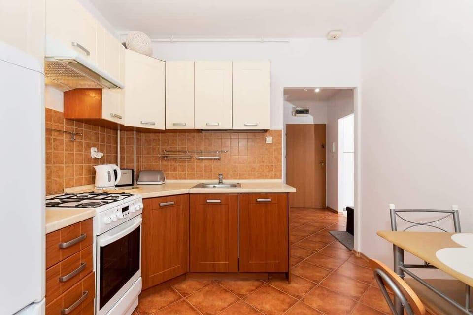 A cozy kitchen with wooden cabinetry, a small table, and two chairs. The dining area is compact and has a warm, inviting feel.