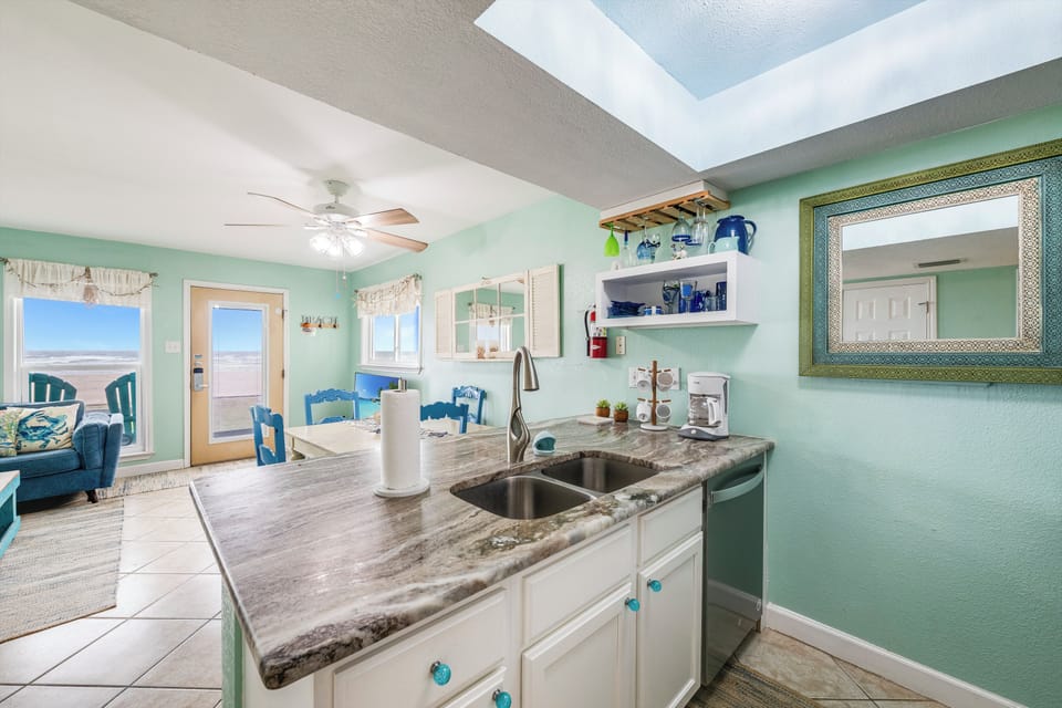 Your fully equipped kitchen opens to coastal views, with granite counters and ocean-themed touches creating the perfect beachside cooking space.