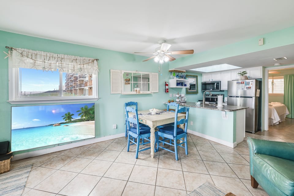 Your open-concept kitchen and dining area features tropical mint walls, beach-themed artwork, and everything needed for memorable meals together.