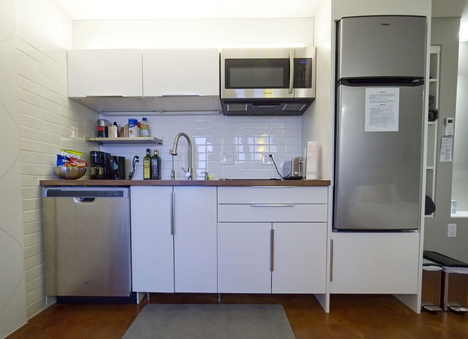 Kitchenette with coffee, fridge, dishes, dishwasher, microwave, and stovetop.