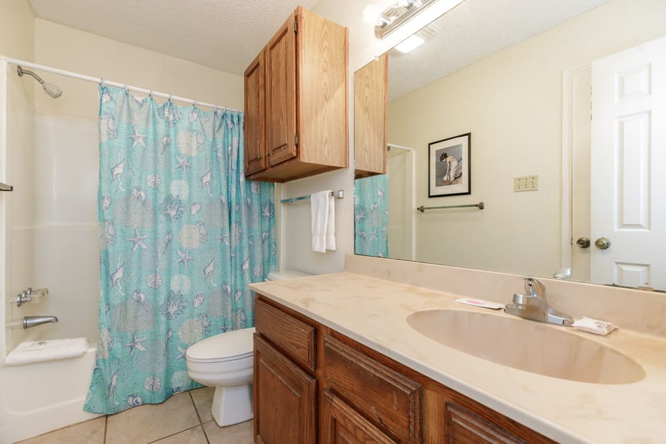 Freshen up in your spacious bathroom featuring a relaxing tub-shower combo and coastal-themed touches that bring the beach vibes indoors.