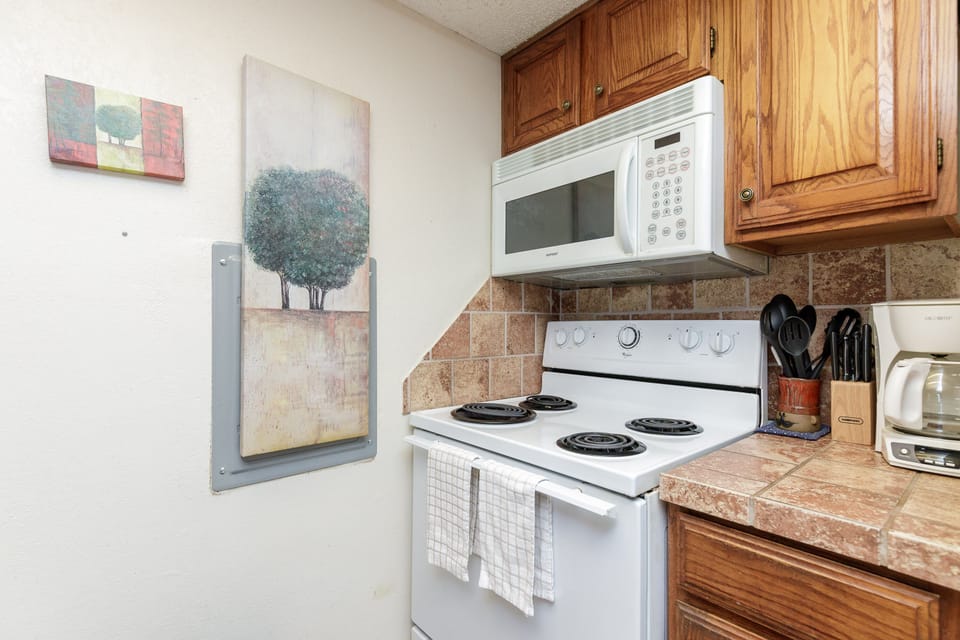 Your fully equipped kitchen awaits with warm wood cabinets, stone countertops, and everything needed for home-cooked meals during your stay.