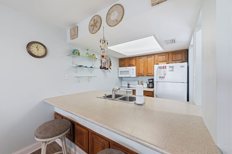 You'll love the fully-equipped kitchen with modern appliances, warm wood cabinetry, and coastal-themed decor, ready for preparing your favorite meals during your stay.