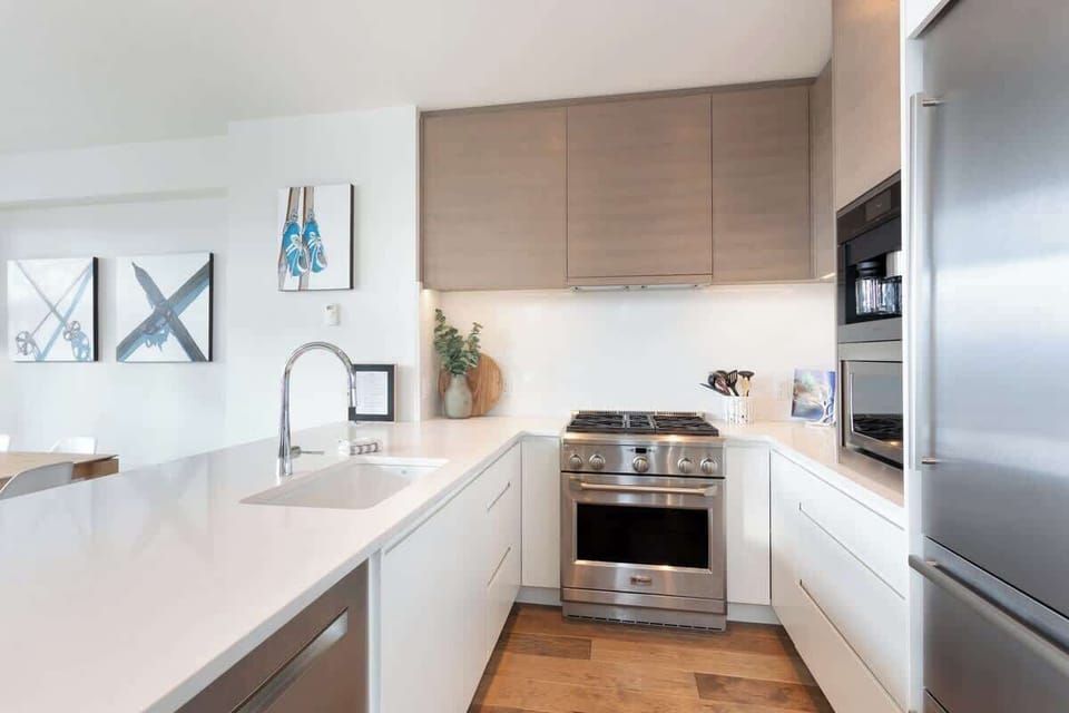 - Bright modern kitchen with premium stainless steel appliances and sleek finishes  
- Open layout with white countertops and wood cabinetry for a warm mountain feel  
- Fully equipped for home-cooked meals after a day on the slopes  