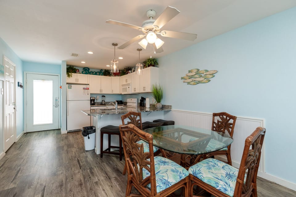Step into your bright coastal retreat where ocean-themed dining meets fully equipped kitchen convenience, all bathed in soothing sea glass hues.