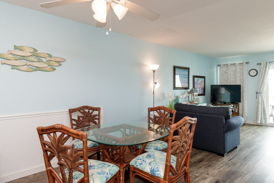 Your coastal-themed living space features tropical dining chairs and soothing ocean hues, creating the perfect spot to unwind after beach adventures.