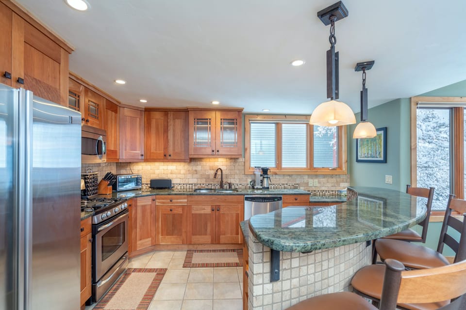 The fully equipped kitchen of this 2 bedroom condo in Telluride, with breakfast bar and stainless steel appliances.