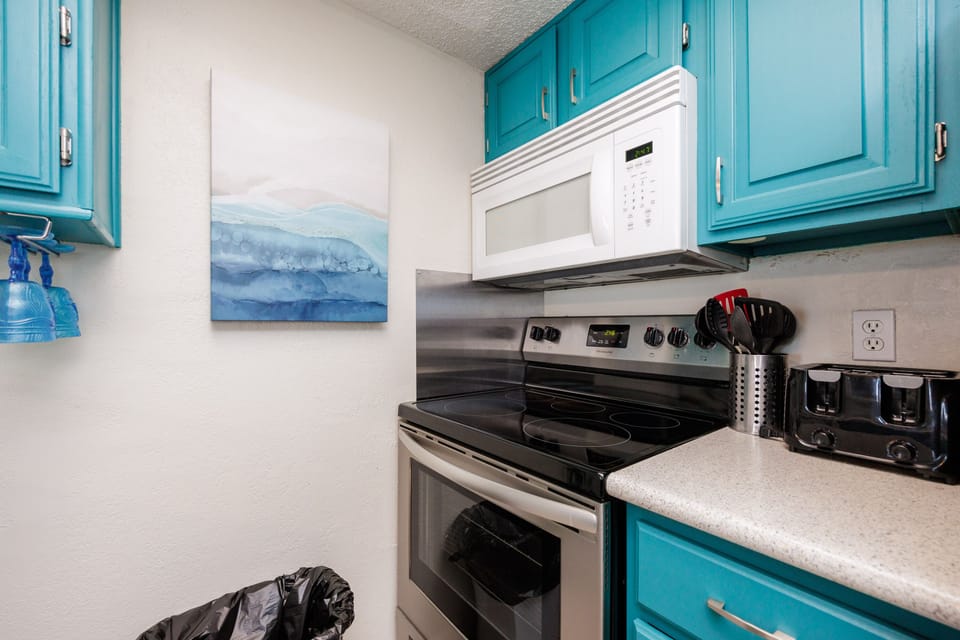 Your fully equipped kitchen features turquoise cabinets and modern appliances, creating a vibrant space where you can prepare meals with ocean-inspired charm.