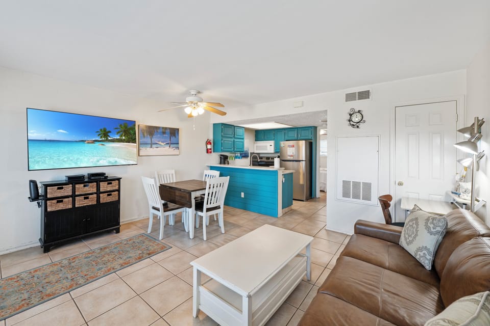 Relax in your open-concept retreat with turquoise kitchen, leather sofa, and large TV perfect for unwinding after beach days.