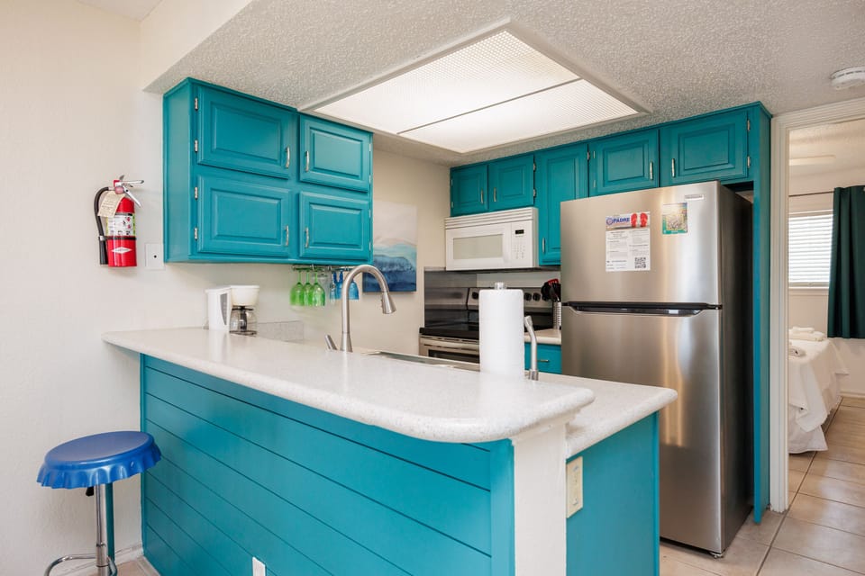 Your vibrant turquoise kitchen awaits with modern appliances, granite counters, and everything needed to create delicious vacation memories.