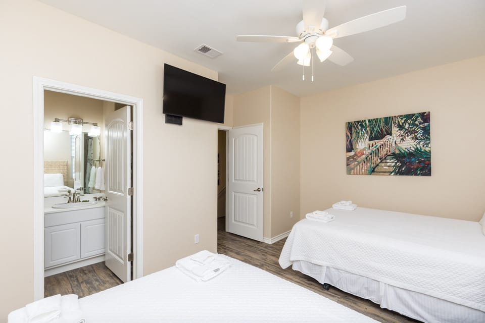 Unwind in your peaceful bedroom with twin beds, ceiling fan, and private bathroom access for ultimate comfort.