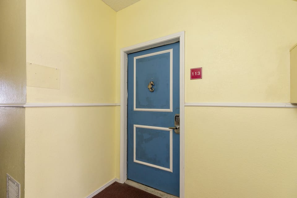 Your cheerful blue door marks the entrance to your coastal retreat, where room 113 awaits with nautical charm and home-like comfort.