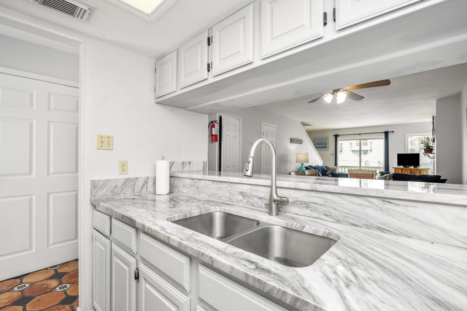 Your bright kitchen features marble countertops, crisp white cabinets, and an open layout connecting to the living area.