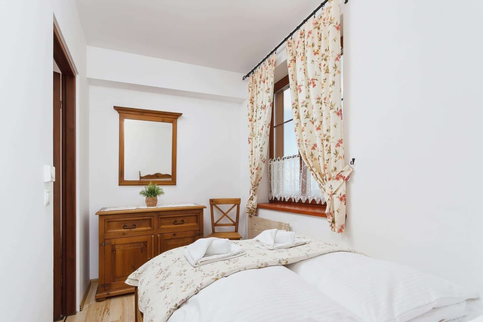Another bedroom with wooden furniture, including a bed with a floral duvet and a simple nightstand.