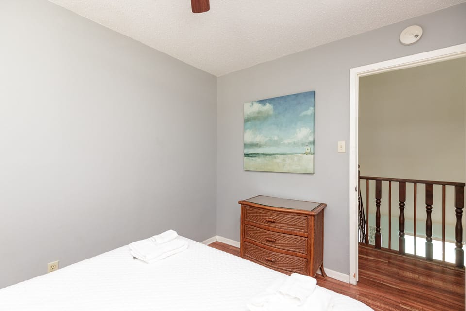 Rest peacefully in your serene bedroom with coastal artwork and warm wood accents creating a tranquil retreat.