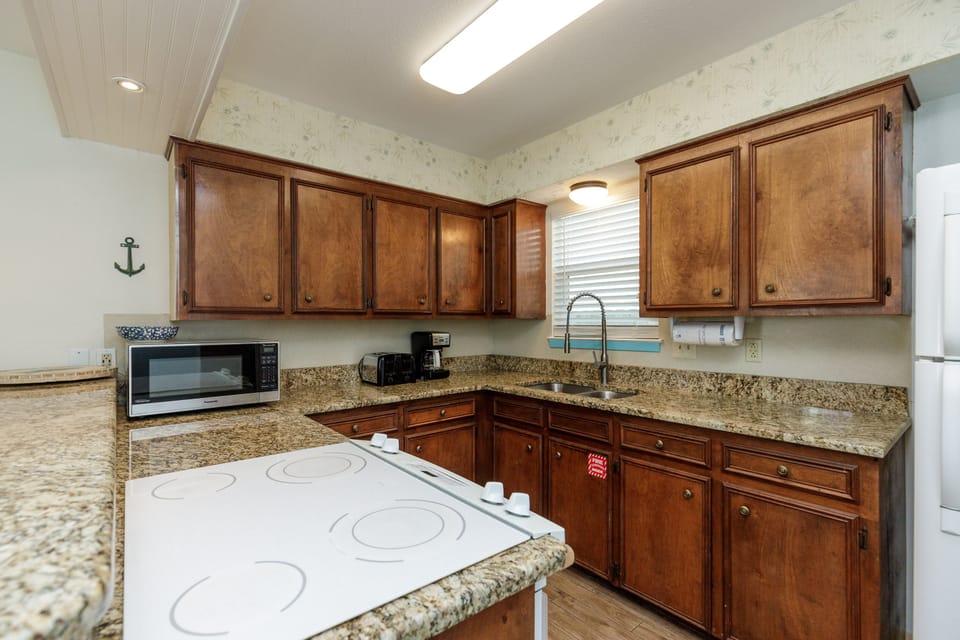 Your fully equipped kitchen features rich wooden cabinets, granite countertops, and modern appliances, creating the perfect space for preparing meals.