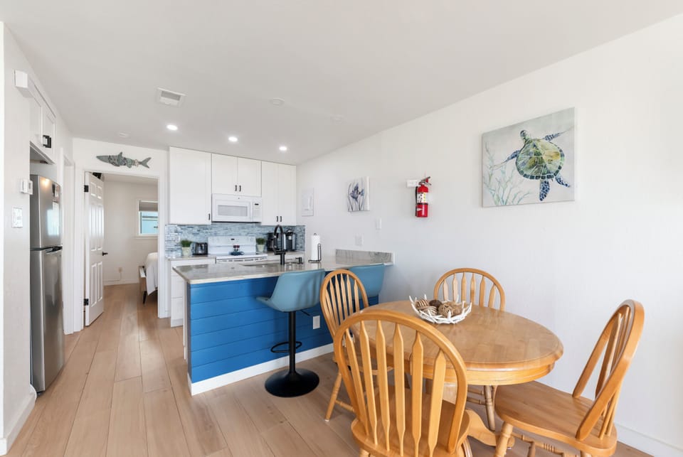 Gather around the inviting dining table with ocean-themed art adorning the walls, then step into your modern kitchen with white cabinetry, bar seating, and everything you need to prepare your favorite meals together.