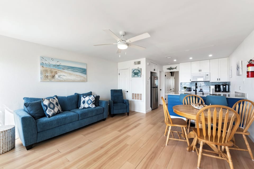 Kick back on the plush sofa or gather around the warm wood dining table in your bright, coastal-themed living space with convenient kitchen access.