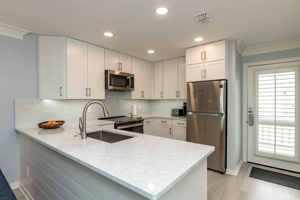 Your fully equipped kitchen features sleek white cabinets, granite countertops, and stainless steel appliances for all your culinary needs.