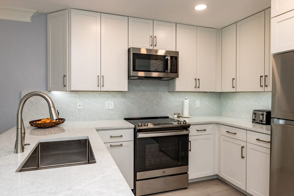 Your modern kitchen features pristine white cabinets, sleek stainless appliances, and gleaming countertops perfect for preparing meals during your stay.