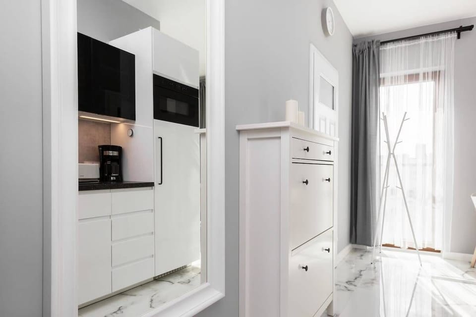A sleek kitchenette featuring white cabinets, a black countertop, and integrated appliances such as a stovetop and coffee maker, perfectly suited for a compact living space.