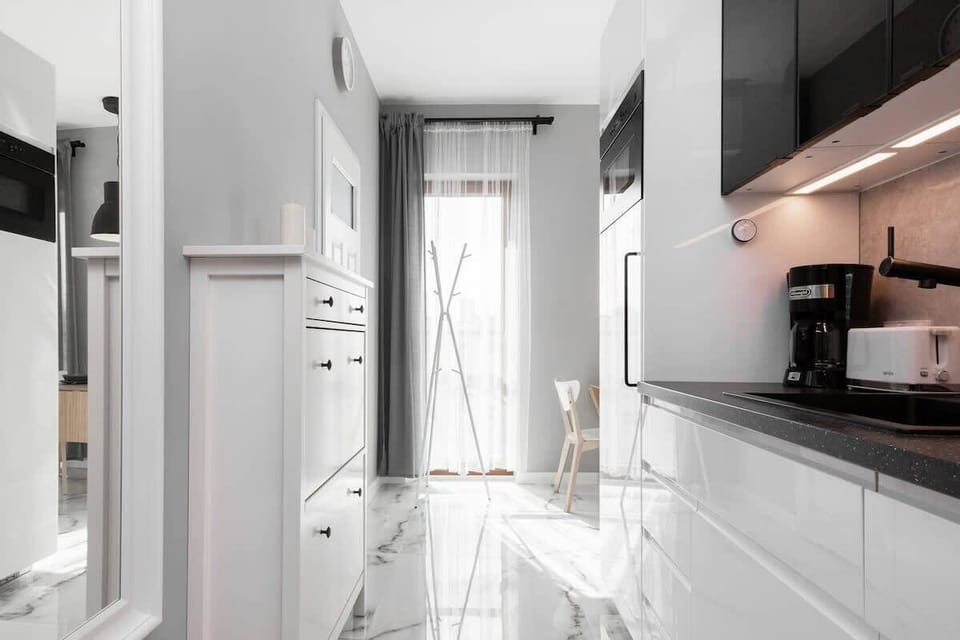 A bright kitchen area with white and black elements, enhanced by natural light from an adjacent window.