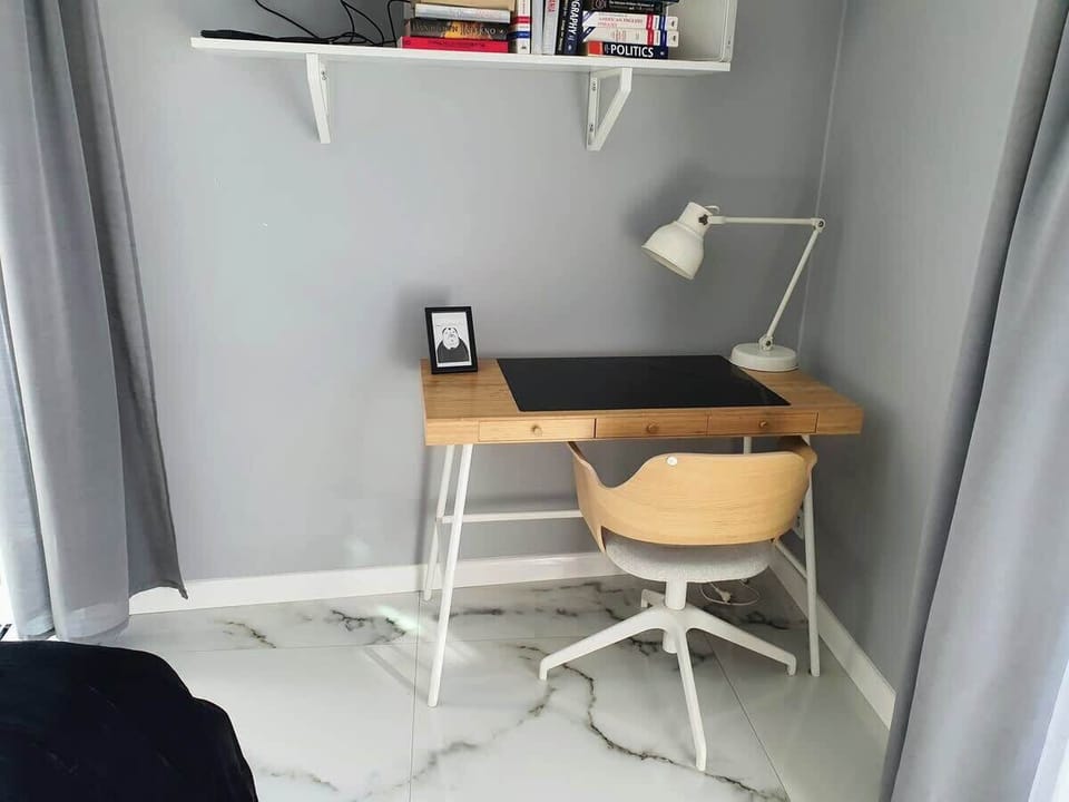 A workspace with a chair and desk positioned by a large window for optimal lighting.