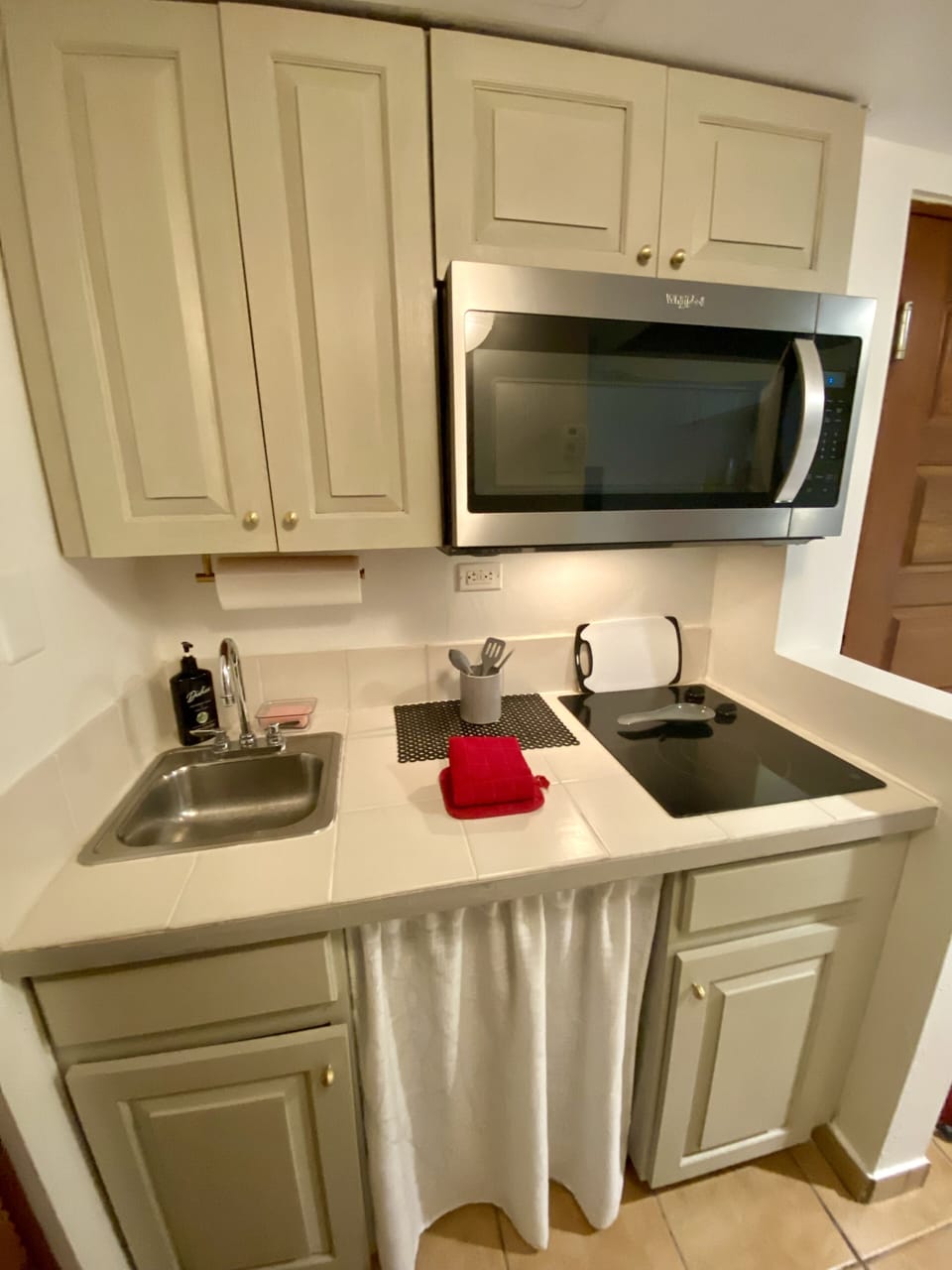 Kitchenette with plates, utensils, coffee maker, pots, and pans.