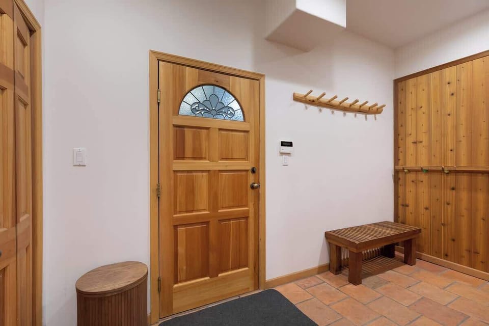- Entryway with rustic wood accents and tiled floor for easy gear storage  
- Bench seating and coat hooks make it perfect for ski or hiking trips  
- Welcoming mountain-style entrance for guests coming in from the snow 