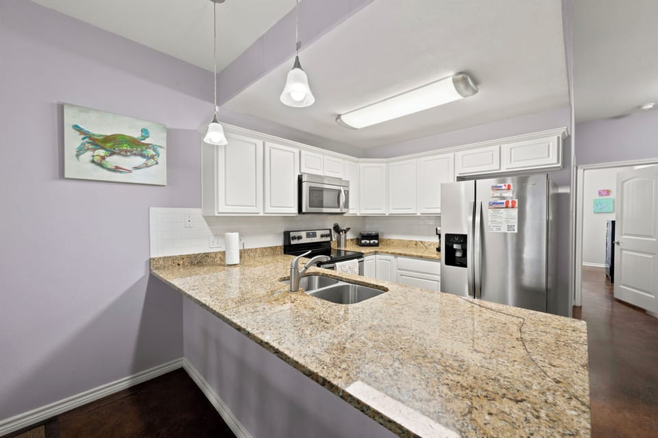 Prepare your favorite dishes in this bright, fully equipped kitchen featuring granite countertops, stainless steel appliances, and plenty of cabinet space for all your culinary needs.