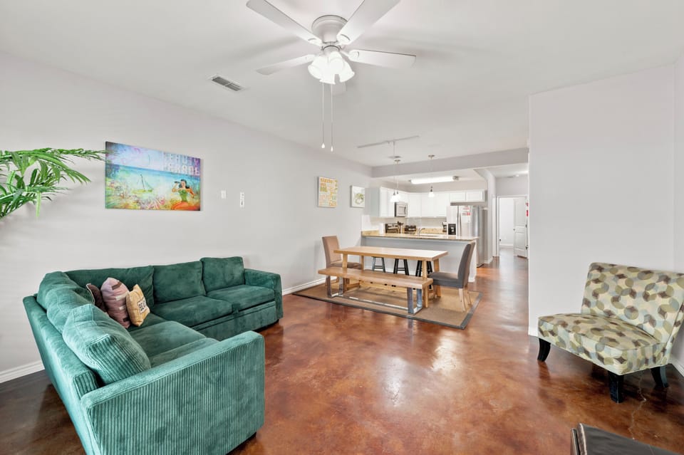 Settle into your spacious open-concept living area where a plush green sectional and stylish dining space invite you to relax and connect. Gleaming polished floors catch the light while your modern kitchen awaits just steps away.