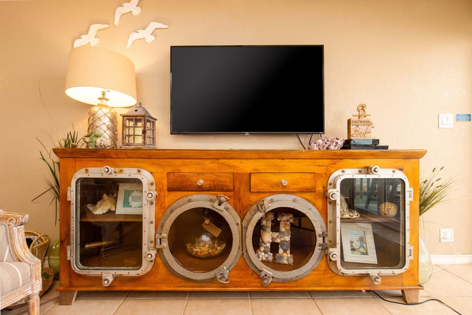 Unwind in your unique living space featuring a nautical-themed entertainment center with porthole windows and maritime charm.