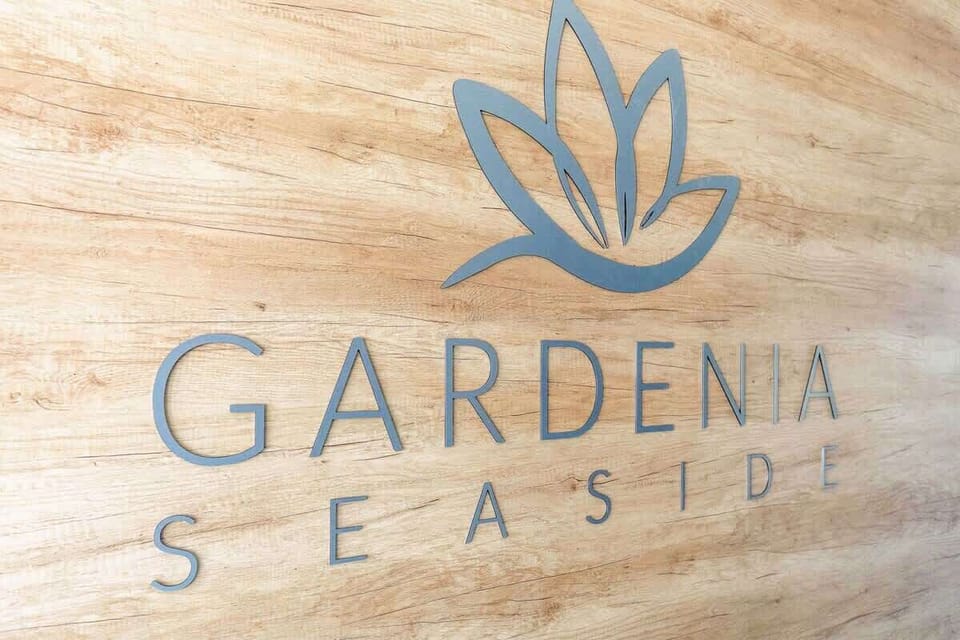 A sign with the "Gardenia Seaside" logo displayed on a textured floor, emphasizing the branding of the apartment complex.