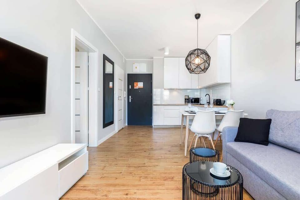 An open-plan area with a kitchenette and dining table, blending into the living space decorated with blue accents and natural light.
