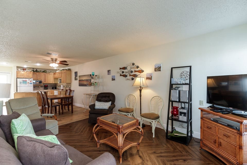Relax in your spacious open-concept living area with coastal charm, featuring comfortable seating, dining space, and fully equipped kitchen for memorable meals.