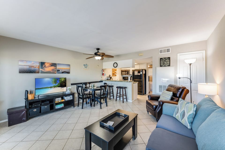 Relax in your spacious living room with comfortable seating, large TV, and open kitchen design perfect for entertaining guests.