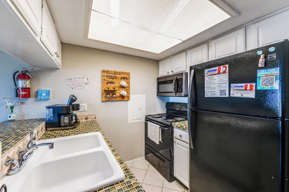 Your fully-equipped kitchen features everything needed for home-cooked meals, from morning coffee to evening dinners, with natural light streaming through the skylight above.