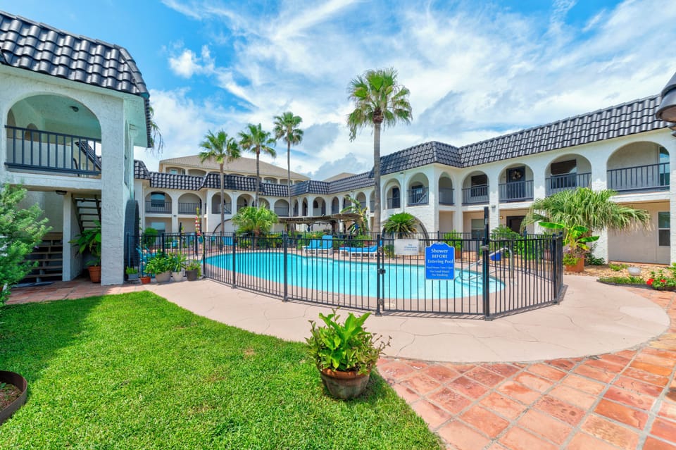 Spanish-style resort property featuring white stucco buildings with traditional tile roofs surrounding a central swimming pool area.