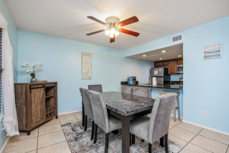 Your dining space features coastal blue walls and elegant seating, perfectly connected to your fully-equipped kitchen for memorable meals together.
